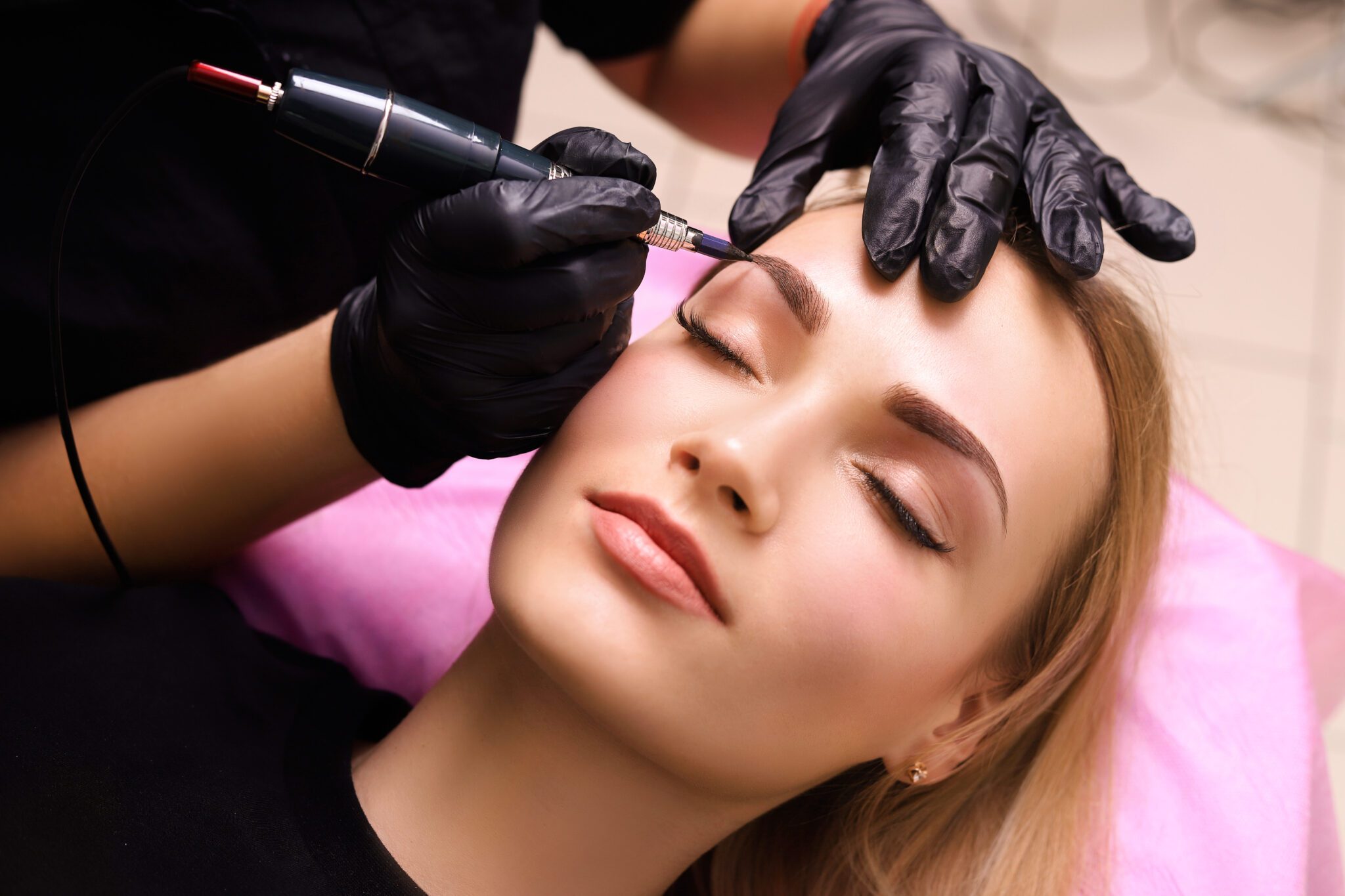 Cosmetologist applying permanent make up on eyebrows- eyebrow tattoo.